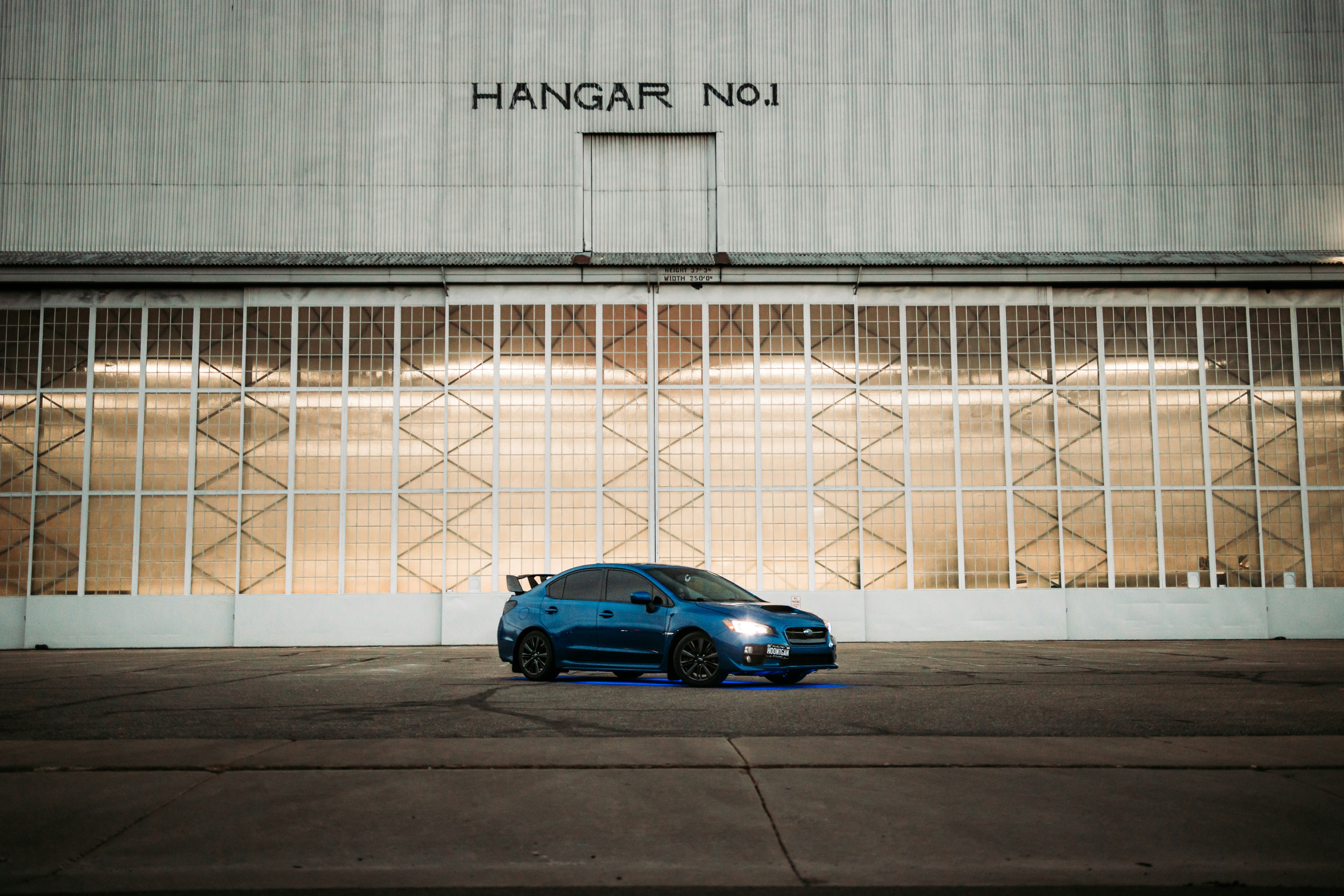 blue sedan parked beside white metal fence